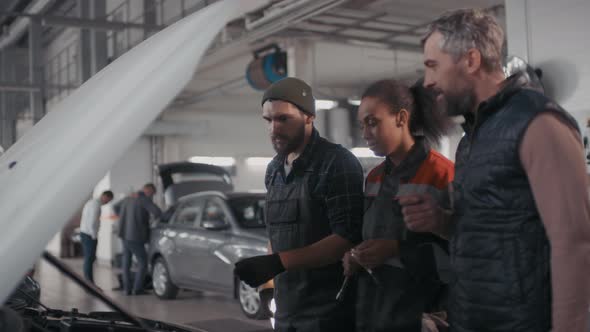 Auto Mechanics Diagnosing Problem in Clients Car alt