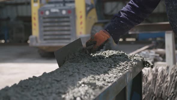 Workers pouring concrete into large steel molds on a construction site alt
