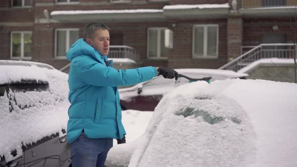 Person Driver Cleans the Car From Snow with a Brush