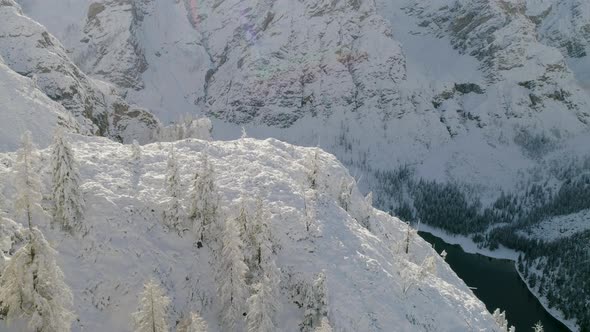 Breath taking aerial view establishing over snow covered mountain forest slopes reveal Italian Lago alt