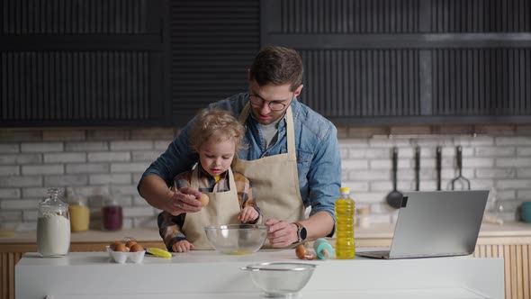 Dad and Little Son are Spending Time Together at Kitchen Child is Studying to Cook Breaking Eggs in alt