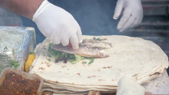 Man Is Cooking Making Ekmek with Fish at Street Market, Hands in Gloves Closeup. alt