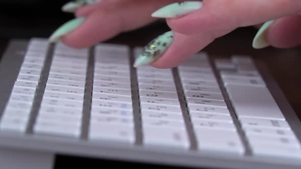 Fingers of a Young Girl are Typing on the Keyboard of a White Laptop alt