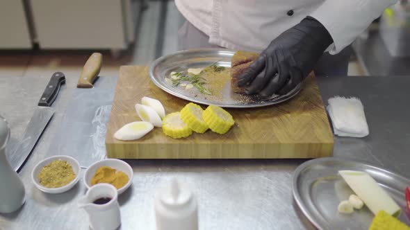 Professional Chefs Hands in Black Latex Gloves Rubs a Piece of Veal in the Metal Plate, Marinating alt