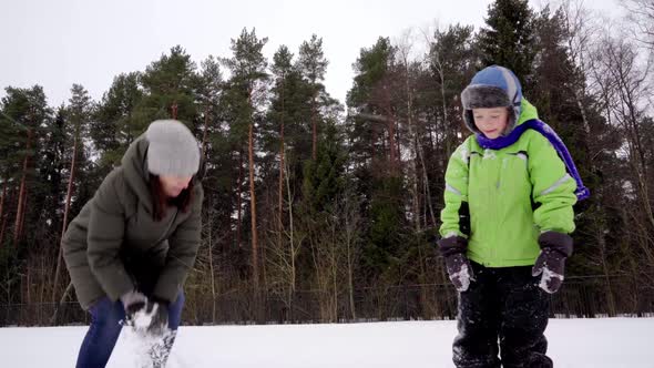 Happy cute Caucasian mom and son 5 years old have fun playing snowballs alt