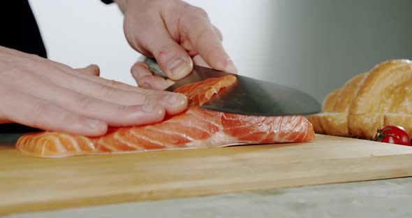 Slow Motion. Chef Begins To Cut with a Knife Fish To the Wooden Board. Close Up, alt