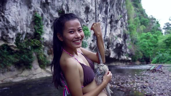 Cute Smiling and Laughing Asian Girl in Bikini on a Rope in the River Thailand alt