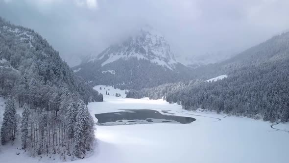 Beautiful flight over a mountain lake to a mountain in the clouds while winter in Switzerland. Hazy, alt