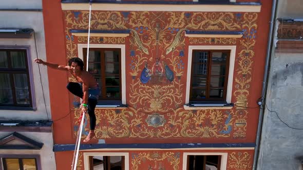 Man Balances on Tight Rope a View of the City From Height alt