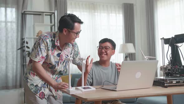 Cheerful Father And His Son Using Laptop Computer Programming Electric Wind Turbine Model alt