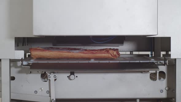 In the Machine on Conveyor Belt Piece of Pork Bacon Passes From Left to Right