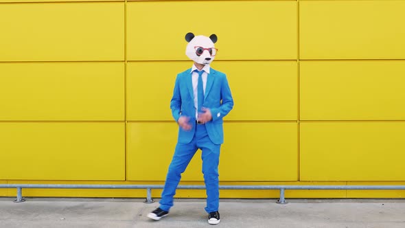 Business couple wearing animal masks dancing in front of yellow wall alt
