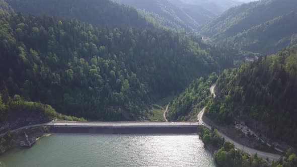 Aerial shot of reservoir amongst the valley with green woodland clear skies alt