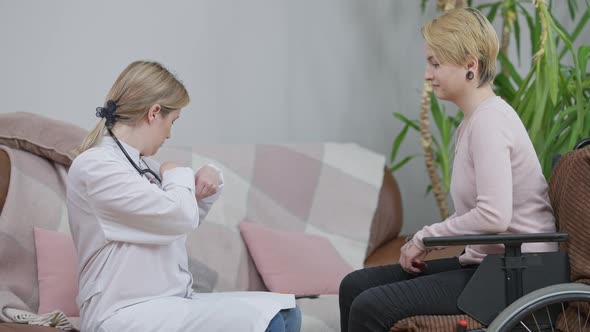 Young Paraplegic Woman Paying Professional Doctor for Consultation at Home alt