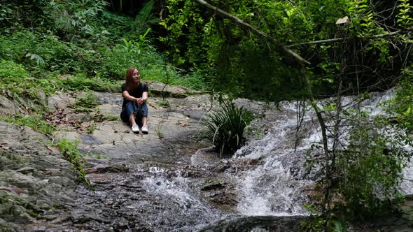 A female traveler sitting by the waterfall