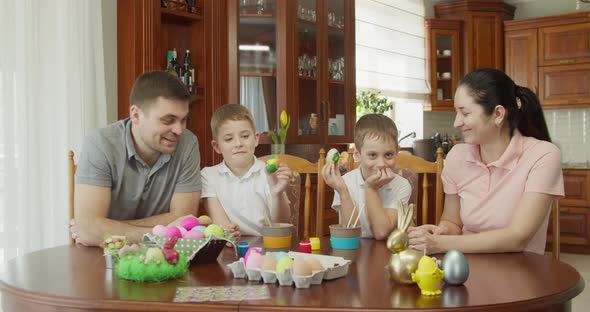 Happy Family Painting Easter Eggs in Kitchen alt