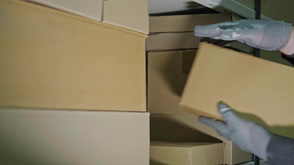 A man in gloves steals box in a warehouse. Problems with theft and security in the office