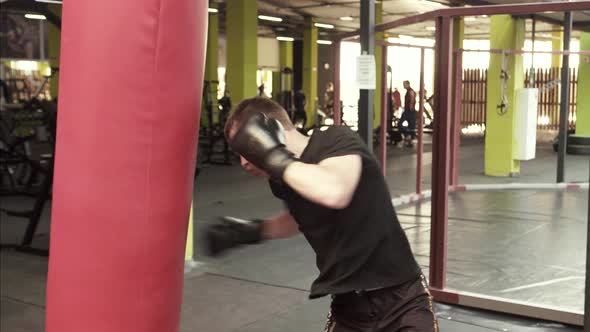 Young Boxer Guy Beats a Punching Bag in the Gym alt