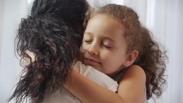Happy Cute Affectionate Adopted Little Kid Girl Hugging Foster Care Parent Mother with Eyes Closed alt