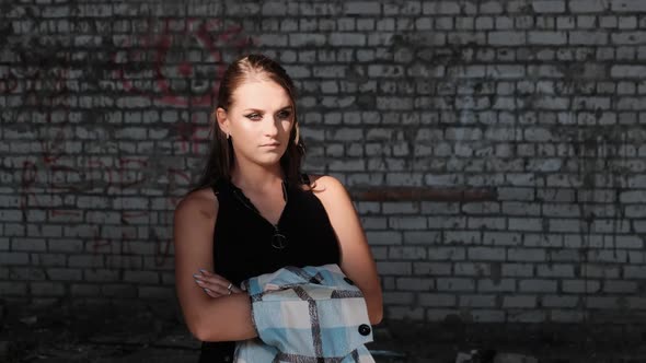Beautiful Young Woman Standing Near the Brick Wall and Looking at the Camera