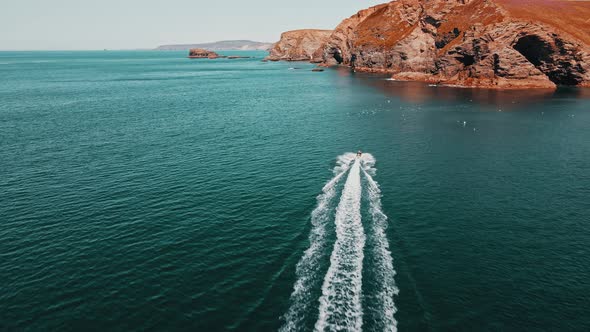 The jet ski runs in the direction of the rock on turquoise water. Aerial view.