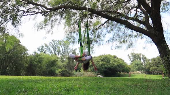 Young Woman Doing Aerial Yoga in a Park on a Sunny Day