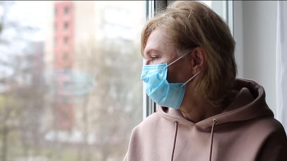 Senior Woman with Medical Mask Near the Window alt