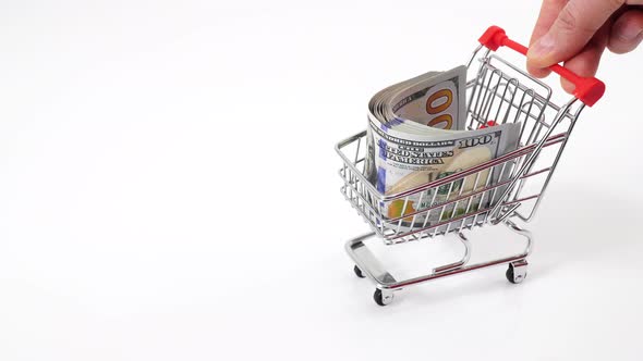 Hand pushing miniature toy supermarket trolley. 