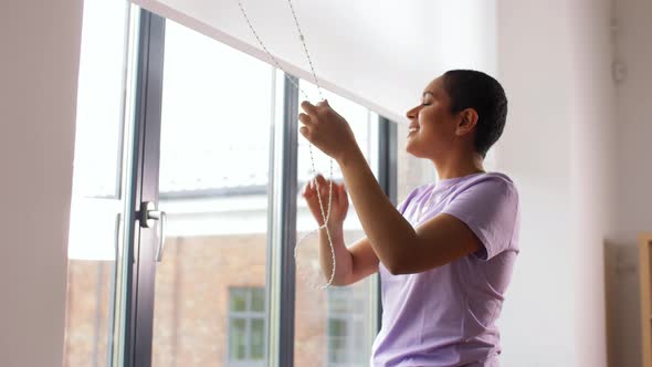 African Woman Closes Window Blinds at Home alt
