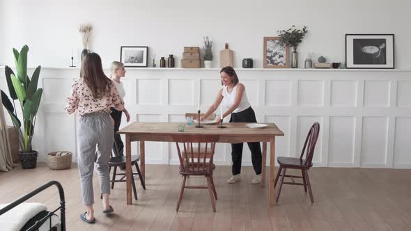 A young woman sets the table for dinner. Woman setting table in stylish kitchen alt