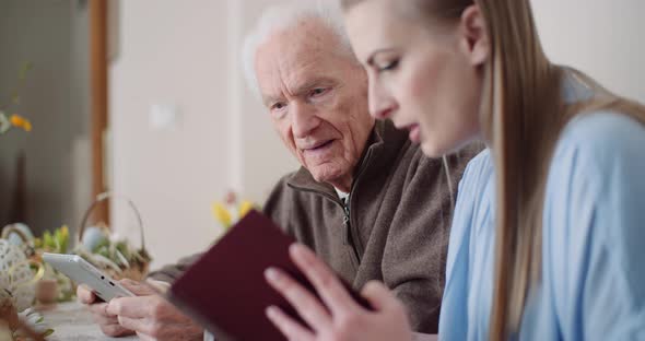 Young Woman Surfing Internet with Grandfather on Digital Tablet alt