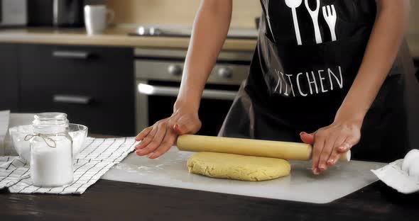 Women's Hands Roll Out the Dough with a Rolling Pin on a Silicone Mat