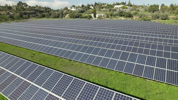 Flying low over photovoltaic farm, solar panels on grass field. Portugal