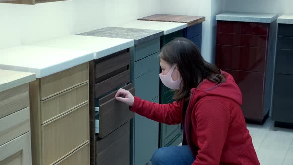 Girl in a Protective Mask Selects a New Kitchen in Store
