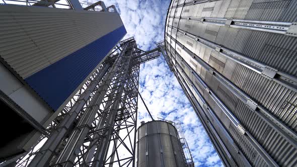 Metal construction on a modern industrial plant. Large grain elevators on beautiful sky background.  alt