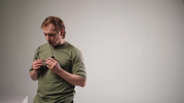 The Man Holds Sunglasses in His Hands and Looks Into the Camera alt