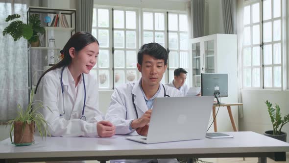 Asian Professional Physicians Talking, Consulting And Working On Laptop Computer alt