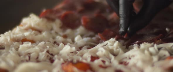 Close up of a chef placing pepperoni layer over cheese on traditional al taglio pizza. alt