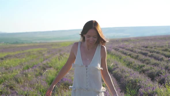 Woman in Lavender Flowers Field at Sunset in White Dress and Hat