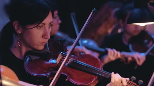 A woman playing the violin in the theatre close-up. Slow motion