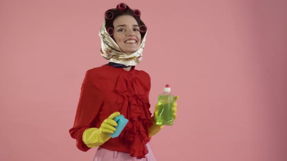 A Young Woman Holds a Dish Detergent a Sponge and Dances