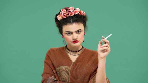 Portrait of Woman Frida Kahlo Lookalike Wearing Handmade Accessories Looking Seriously and Shaking alt