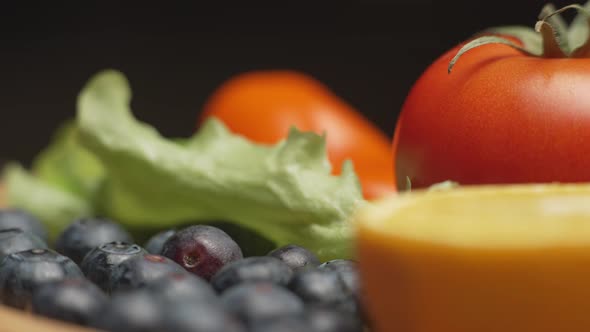 Variety of Color Fruits and Berries and Vegetables with Greens are Rotating on the Plate alt