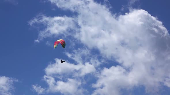 Paraglider on Blue Sky Background and Clouds alt