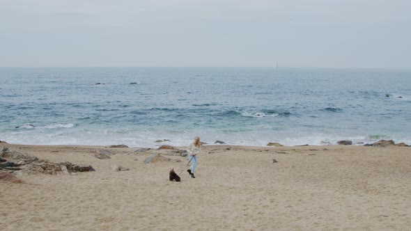 Woman Is Walking With Dog On Beach