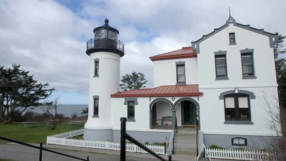 Wide shot pulling away from a restored lighthouse in Washington State. alt