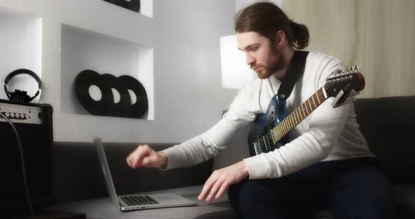 Young Man is Learning to Play the Guitar Online