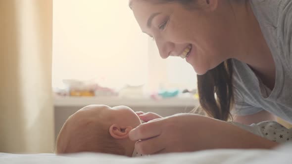 Loving Mother Kisses Cheeks of Little Daughter Holding Hands alt