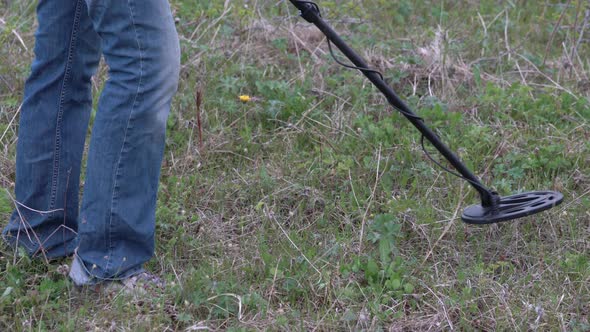 Woman Treasure Hunter with Metal Detector Scanning Ground in Summer Forest