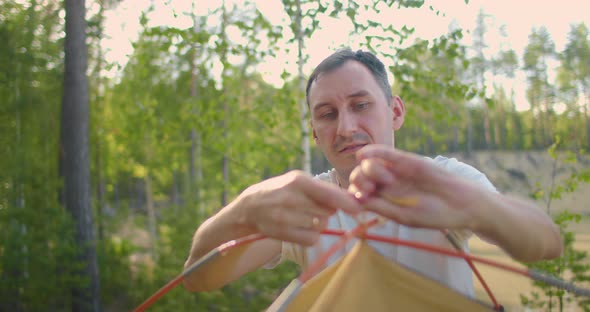 Portrait of a Man Setting Up a Tent in the Woods in Slow Motion alt